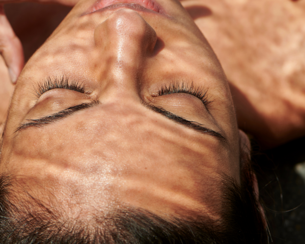 woman's face with eyes closed; does red light therapy help with rosacea